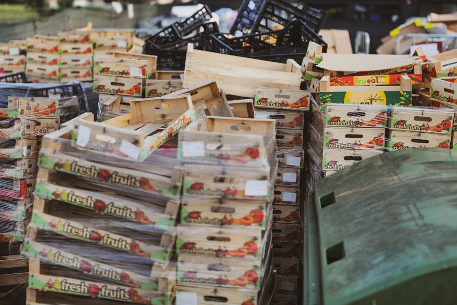Montones de cajas de madera para frutas en un área de mercado al aire libre, ideal para temas de comida o reciclaje.